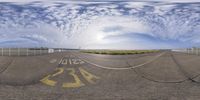 a fish eye view of a runway in the sky and clouds behind it as seen through a fish - eye lens