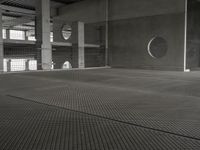 black and white image of a modern industrial building with cement floors and round windows in it