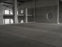 black and white image of a modern industrial building with cement floors and round windows in it