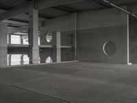 black and white image of a modern industrial building with cement floors and round windows in it