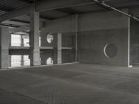 black and white image of a modern industrial building with cement floors and round windows in it