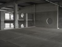 black and white image of a modern industrial building with cement floors and round windows in it