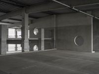 black and white image of a modern industrial building with cement floors and round windows in it