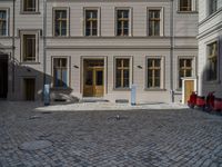 an empty parking lot with plants in the ground and on the side of the building, there is an enclosed area and windows