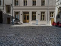 an empty parking lot with plants in the ground and on the side of the building, there is an enclosed area and windows