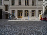 an empty parking lot with plants in the ground and on the side of the building, there is an enclosed area and windows