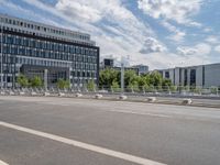 a empty road with a bunch of metal buildings in the background while parked bicycles are parked