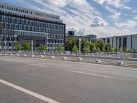 a empty road with a bunch of metal buildings in the background while parked bicycles are parked