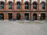 bicycles lined up in front of two brick building in germany, with red brick, round, arched, arched, and arched windows