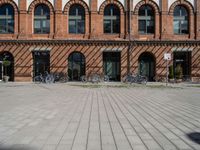 bicycles lined up in front of two brick building in germany, with red brick, round, arched, arched, and arched windows