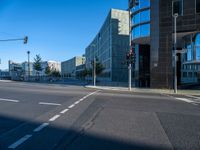 the sun is shining on a empty road in front of large buildings and traffic lights