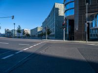 the sun is shining on a empty road in front of large buildings and traffic lights