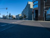 the sun is shining on a empty road in front of large buildings and traffic lights