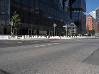 an empty road that has a street sign by it on the side of it and another white pole near the road