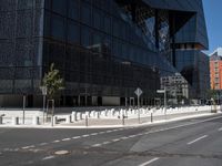 an empty road that has a street sign by it on the side of it and another white pole near the road