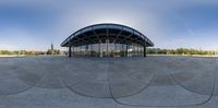 a fish eye view of a building with curved glass walls and walkways in the sun