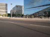 a street near some tall buildings with a reflection on the glass wall in front of them