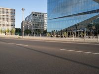 a street near some tall buildings with a reflection on the glass wall in front of them