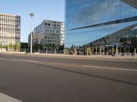 a street near some tall buildings with a reflection on the glass wall in front of them