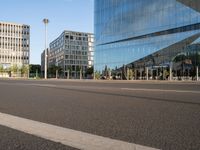 a street near some tall buildings with a reflection on the glass wall in front of them