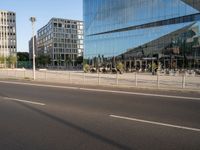 a street near some tall buildings with a reflection on the glass wall in front of them