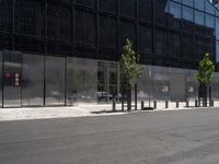 a person riding a bicycle near an elevator door near some trees and metal poles in front of a building