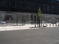 a person riding a bicycle near an elevator door near some trees and metal poles in front of a building