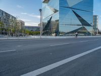 there is a man riding a bike near the side of a building with a glass tower