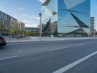 there is a man riding a bike near the side of a building with a glass tower