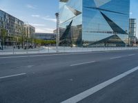 there is a man riding a bike near the side of a building with a glass tower