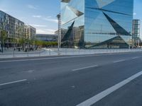 there is a man riding a bike near the side of a building with a glass tower