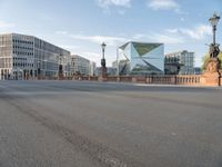 an empty city street with buildings in the back ground and a fence and traffic light