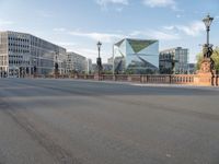 an empty city street with buildings in the back ground and a fence and traffic light