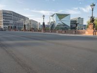 an empty city street with buildings in the back ground and a fence and traffic light