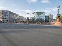 an empty city street with buildings in the back ground and a fence and traffic light