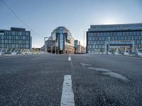 empty streets are shown on either side of the buildings, with blue skies and sunshine shining