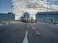 view from an empty road towards buildings at sunset, with only one lane leading up to the other side