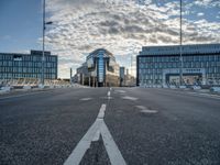 view from an empty road towards buildings at sunset, with only one lane leading up to the other side