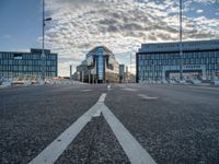 view from an empty road towards buildings at sunset, with only one lane leading up to the other side