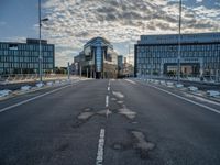 view from an empty road towards buildings at sunset, with only one lane leading up to the other side