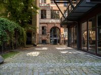 a cobblestone paved patio near an old brick building with two balconies