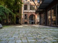 a cobblestone paved patio near an old brick building with two balconies