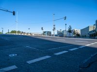 a empty street with buildings in the background on a sunny day and traffic lights illuminating by