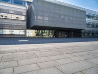 a large glass building with a very big door and windows that is on top of the brick street