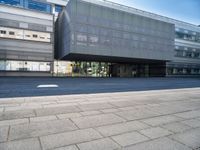 a large glass building with a very big door and windows that is on top of the brick street