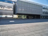 a large glass building with a very big door and windows that is on top of the brick street