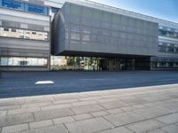 a large glass building with a very big door and windows that is on top of the brick street