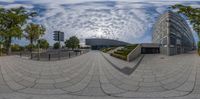 a fish - eye view of a building by trees with clouds in the sky, on a sunny day