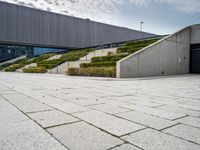 a large open courtyard and stairs with many trees in it by the building and the entrance