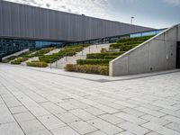 a large open courtyard and stairs with many trees in it by the building and the entrance